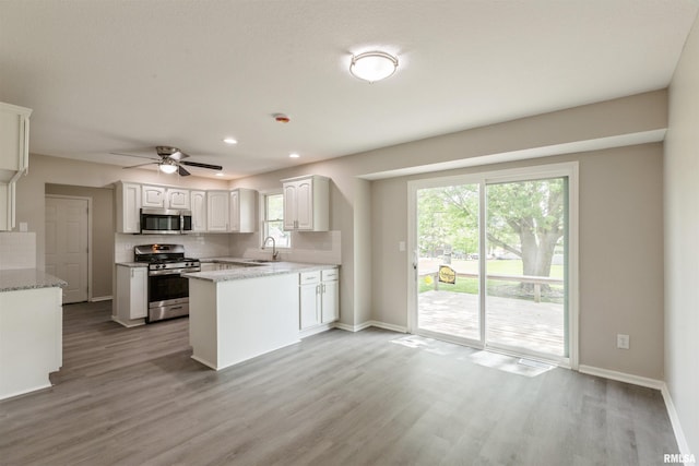 301 5th St, Matherville, IL 61263 - kitchen with stainless steel appliances, a sink, light wood-type flooring, white cabinets, and baseboards