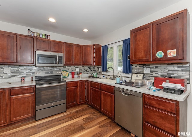 2908 N 4th St, Clinton, IA 52732 - kitchen featuring appliances with stainless steel finishes, a sink, light countertops, light wood-style flooring, and decorative backsplash