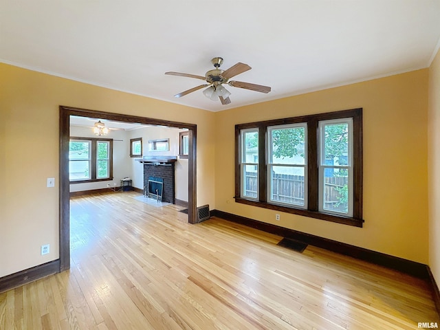 308 E Central Park Ave, Davenport, IA 52803 - unfurnished living room with baseboards, light wood-style flooring, a ceiling fan, crown molding, and a fireplace