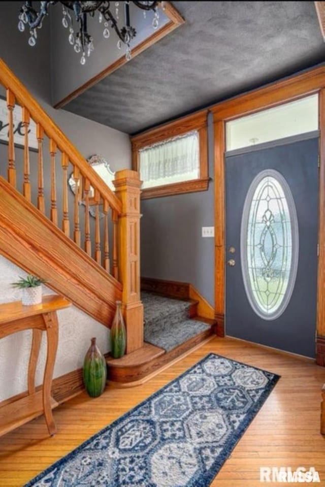 109 W 6th St, Wilton, IA 52778 - foyer entrance featuring stairs, a chandelier, wood finished floors, and baseboards