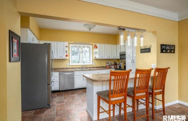 109 W 6th St, Wilton, IA 52778 - kitchen with appliances with stainless steel finishes, white cabinetry, a kitchen bar, stone finish flooring, and ornamental molding