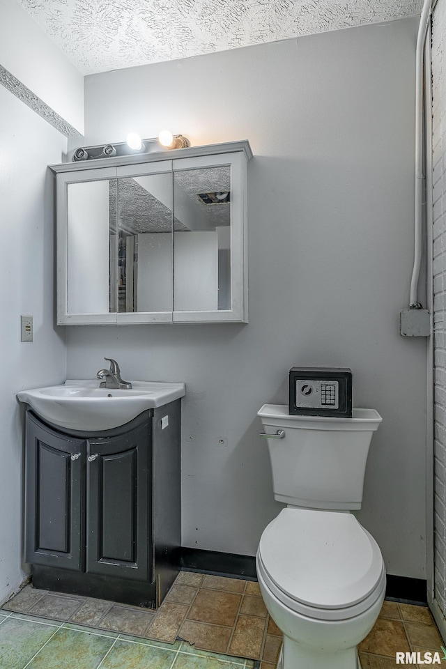 1656 Hitching Post Ln, Davenport, IA 52806 - bathroom with vanity, toilet, baseboards, stone finish flooring, and a textured ceiling
