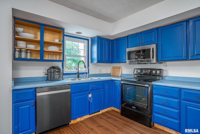 1656 Hitching Post Ln, Davenport, IA 52806 - kitchen with appliances with stainless steel finishes, a sink, blue cabinets, dark wood-style floors, and light countertops