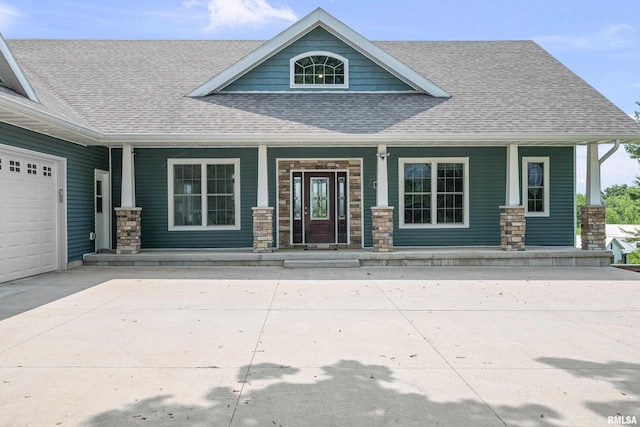 1335 N Utah Ave, Davenport, IA 52804 - entrance to property with a porch, a shingled roof, a garage, stone siding, and concrete driveway