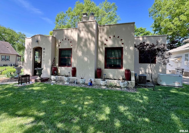 3752 12th St, Rock Island, IL 61201 - rear view of house with stucco siding, central AC unit, a lawn, and a chimney