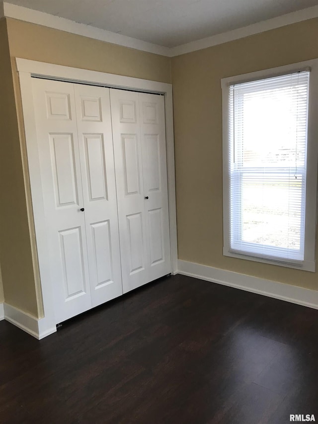 211 Chestnut St, Cambria, IL 62915 - unfurnished bedroom featuring multiple windows, dark wood-style flooring, a closet, and crown molding