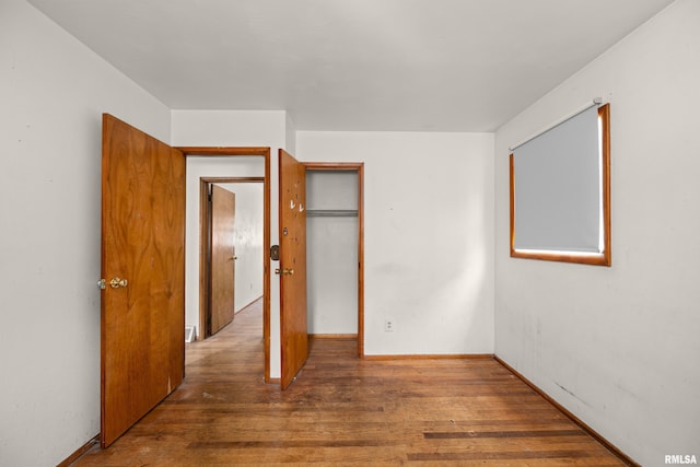 1206 10th Ave N, Clinton, IA 52732 - unfurnished bedroom featuring wood finished floors, baseboards, and a closet