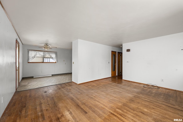 1206 10th Ave N, Clinton, IA 52732 - unfurnished room featuring baseboard heating, wood finished floors, ceiling fan, and baseboards