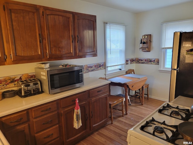2322 4th St Unit A, East Moline, IL 61244 - kitchen featuring freestanding refrigerator, stainless steel microwave, white gas range oven, and light wood-type flooring