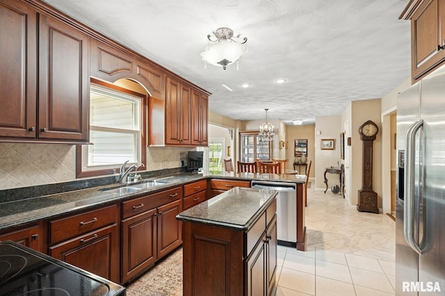 741 12th Ave N, Clinton, IA 52732 - kitchen featuring appliances with stainless steel finishes, a sink, a chandelier, a peninsula, and tasteful backsplash