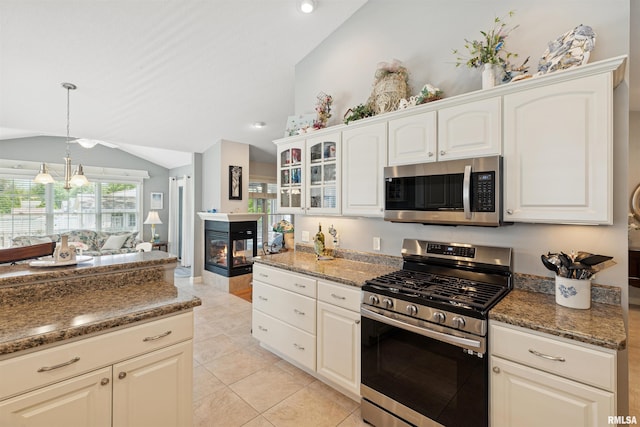 1361 Pinnacle Pines Ct, Bettendorf, IA 52722 - kitchen with appliances with stainless steel finishes, lofted ceiling, a multi sided fireplace, light tile patterned floors, and white cabinets