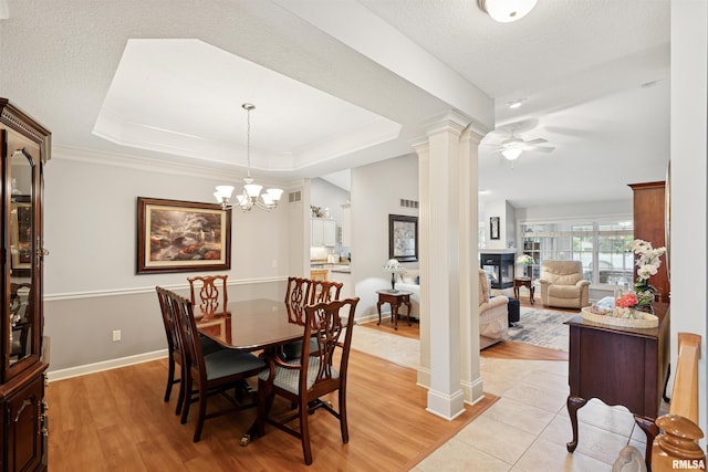 1361 Pinnacle Pines Ct, Bettendorf, IA 52722 - dining area featuring decorative columns, a raised ceiling, light wood finished floors, a ceiling fan, and crown molding