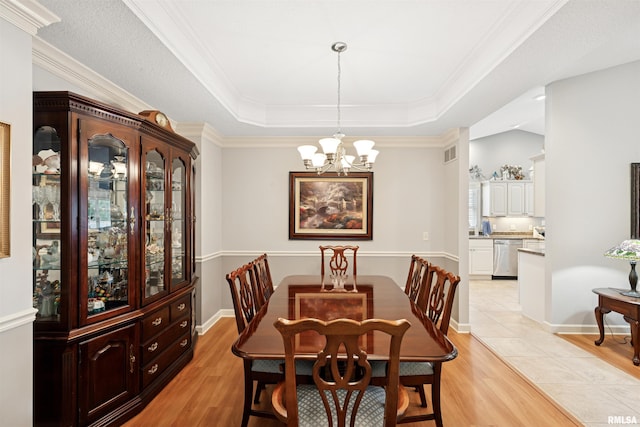 1361 Pinnacle Pines Ct, Bettendorf, IA 52722 - dining room with a raised ceiling, a chandelier, light wood-style flooring, and crown molding