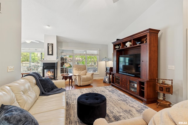 1361 Pinnacle Pines Ct, Bettendorf, IA 52722 - living area with a ceiling fan, wood finished floors, a glass covered fireplace, and vaulted ceiling
