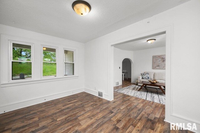 1603 Judson St, Davenport, IA 52803 - spare room featuring arched walkways, dark wood-style flooring, a textured ceiling, and baseboards