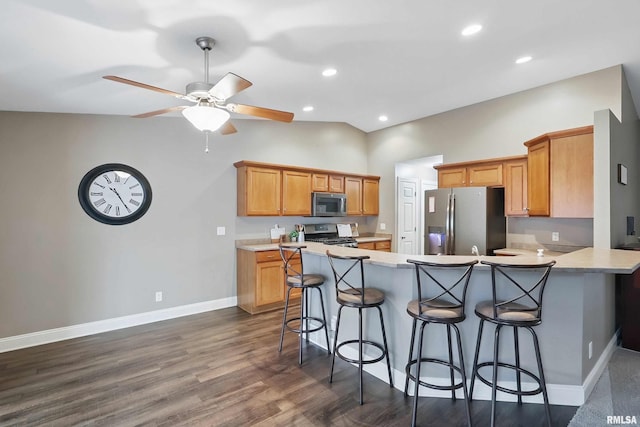 6732 Brookview Ln, Davenport, IA 52806 - kitchen featuring appliances with stainless steel finishes, a peninsula, a kitchen breakfast bar, light countertops, and lofted ceiling