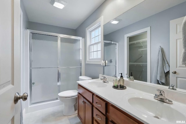6732 Brookview Ln, Davenport, IA 52806 - bathroom featuring a stall shower, double vanity, toilet, tile patterned flooring, and a walk in closet