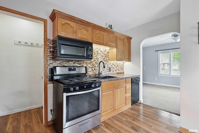 3129 Harrison St, Davenport, IA 52803 - kitchen with black appliances, baseboards, a sink, backsplash, and arched walkways