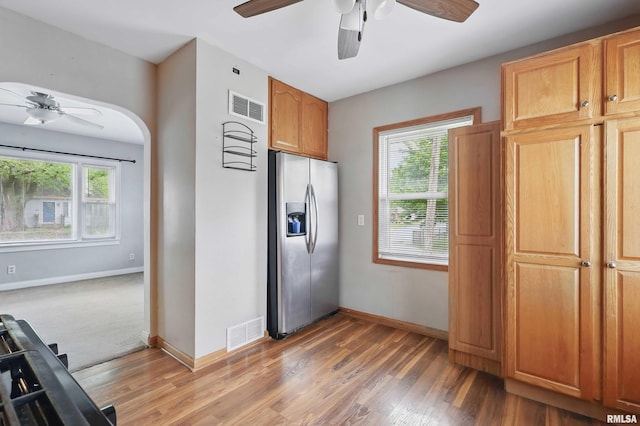 3129 Harrison St, Davenport, IA 52803 - kitchen with stainless steel fridge, ceiling fan, light wood-style floors, baseboards, and arched walkways