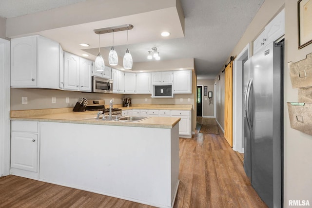 1816 Calico Rd, Marion, IL 62959 - kitchen featuring appliances with stainless steel finishes, a peninsula, wood finished floors, white cabinets, and light countertops