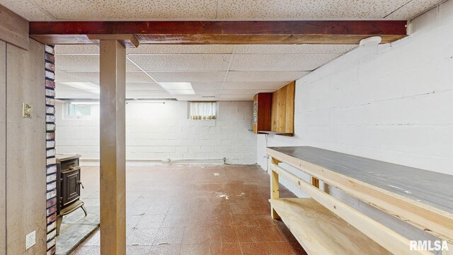 506 18th Ave, Moline, IL 61265 - basement with a paneled ceiling, tile patterned floors, concrete block wall, and a wood stove