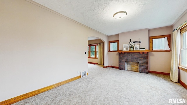 506 18th Ave, Moline, IL 61265 - unfurnished living room with a textured ceiling, carpet, arched walkways, a fireplace, and baseboards