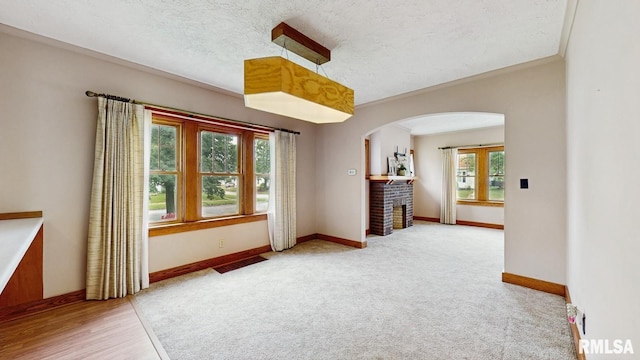 506 18th Ave, Moline, IL 61265 - carpeted spare room featuring arched walkways, baseboards, a fireplace, a textured ceiling, and wood finished floors