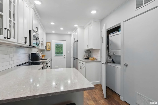 1104 Kimberly Rd Unit 1006, Bettendorf, IA 52722 - kitchen with stacked washing machine and dryer, stainless steel appliances, dark wood finished floors, white cabinets, and tasteful backsplash
