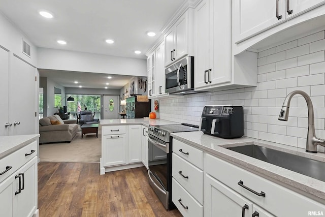 1104 Kimberly Rd Unit 1006, Bettendorf, IA 52722 - kitchen featuring appliances with stainless steel finishes, a sink, white cabinetry, dark wood finished floors, and a peninsula