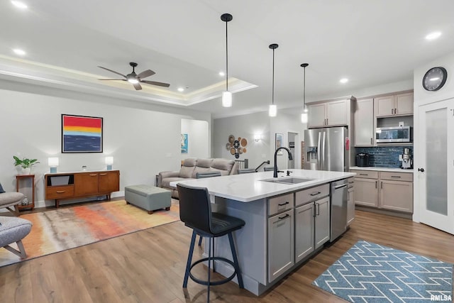1327 Heights Ct, Bettendorf, IA 52803 - kitchen featuring stainless steel appliances, a sink, gray cabinets, open floor plan, and wood finished floors