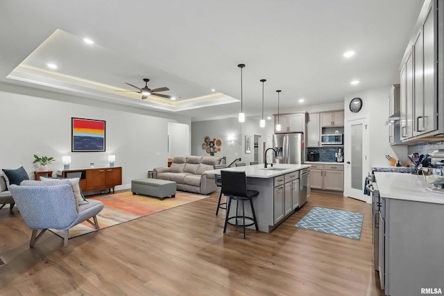 1327 Heights Ct, Bettendorf, IA 52803 - kitchen featuring open floor plan, appliances with stainless steel finishes, gray cabinetry, a sink, and a raised ceiling