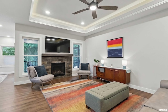 1327 Heights Ct, Bettendorf, IA 52803 - living area featuring a raised ceiling, wood finished floors, a fireplace, a ceiling fan, and baseboards