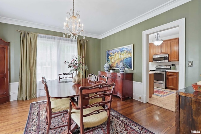 923 22nd St, Moline, IL 61265 - dining space featuring a chandelier, light wood finished floors, crown molding, and a wainscoted wall