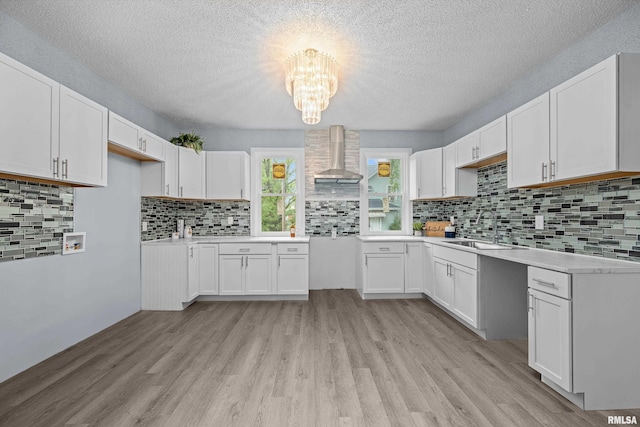 1312 Ripley St, Davenport, IA 52803 - kitchen with a sink, wall chimney exhaust hood, light wood-style floors, a textured ceiling, and a chandelier