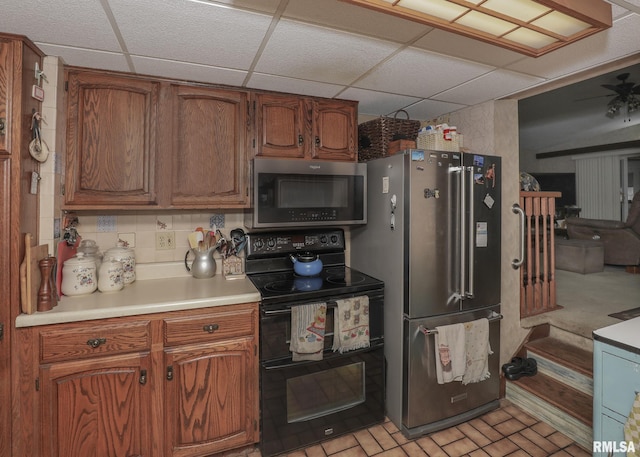 2015 N Zenith Ave, Davenport, IA 52804 - kitchen featuring stainless steel appliances, a drop ceiling, light countertops, brown cabinetry, and decorative backsplash