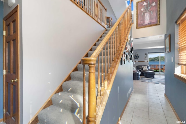 22867 Great River Rd, Le Claire, IA 52753 - stairs with baseboards, tile patterned flooring, and a towering ceiling