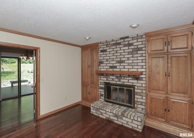 3 Wildwood Trl, Bettendorf, IA 52722 - unfurnished living room featuring a textured ceiling, dark wood-type flooring, ornamental molding, baseboards, and a brick fireplace