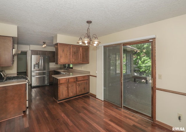 3 Wildwood Trl, Bettendorf, IA 52722 - kitchen featuring appliances with stainless steel finishes, dark wood-style floors, light countertops, a peninsula, and a textured ceiling