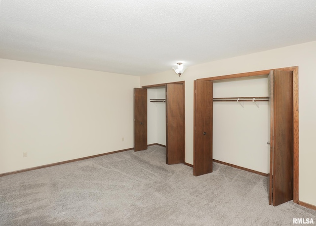 3 Wildwood Trl, Bettendorf, IA 52722 - unfurnished bedroom featuring two closets, light colored carpet, and baseboards