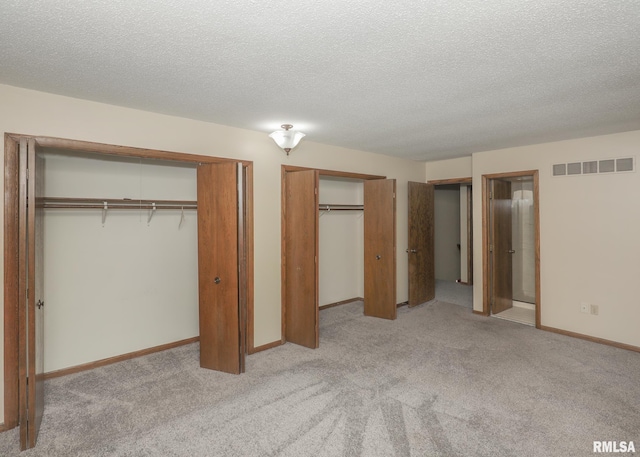 3 Wildwood Trl, Bettendorf, IA 52722 - unfurnished bedroom with two closets, light carpet, a textured ceiling, and baseboards