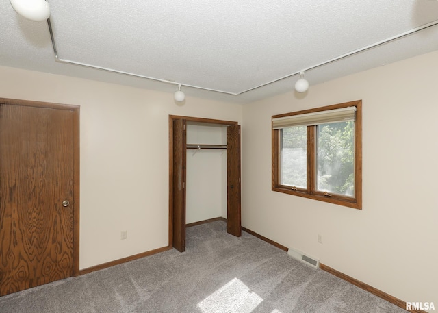 3 Wildwood Trl, Bettendorf, IA 52722 - unfurnished bedroom with track lighting, light colored carpet, a closet, a textured ceiling, and baseboards