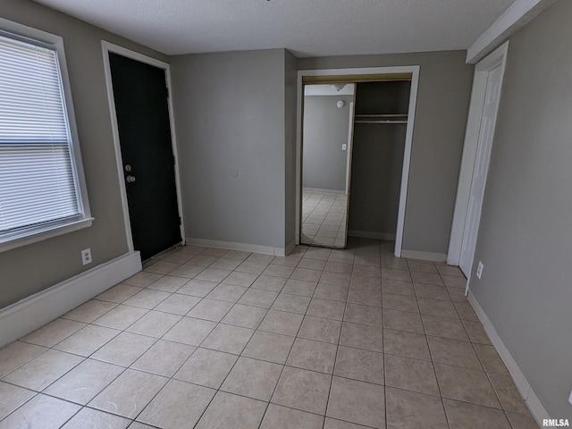 1012 Bridge Ave, Davenport, IA 52803 - unfurnished bedroom with light tile patterned flooring, multiple windows, a textured ceiling, baseboards, and a closet
