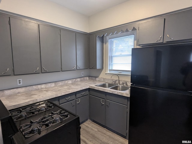 1012 Bridge Ave, Davenport, IA 52803 - kitchen with black appliances, a sink, gray cabinets, light wood-style flooring, and light countertops