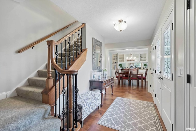 2312 Windsor Dr, Davenport, IA 52807 - foyer with a chandelier, stairs, wood finished floors, and a textured ceiling