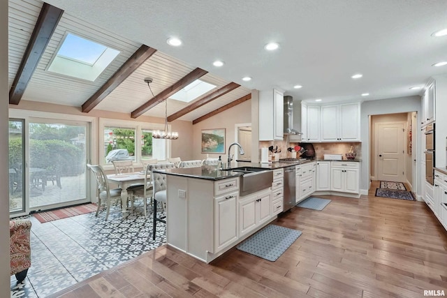 2312 Windsor Dr, Davenport, IA 52807 - kitchen featuring a sink, a skylight, wall chimney range hood, a chandelier, and white cabinets