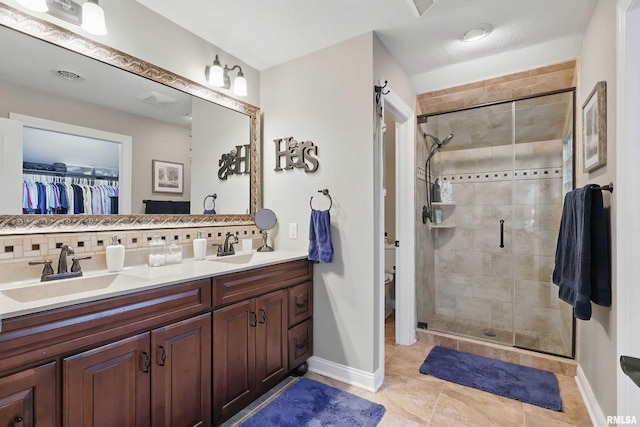 2312 Windsor Dr, Davenport, IA 52807 - bathroom with backsplash, double vanity, a stall shower, toilet, and a walk in closet