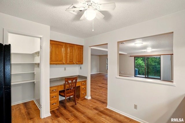 1360 Kimberly Ridge Rd Unit 306, Bettendorf, IA 52722 - home office featuring built in desk, wood finished floors, a textured ceiling, a ceiling fan, and baseboards