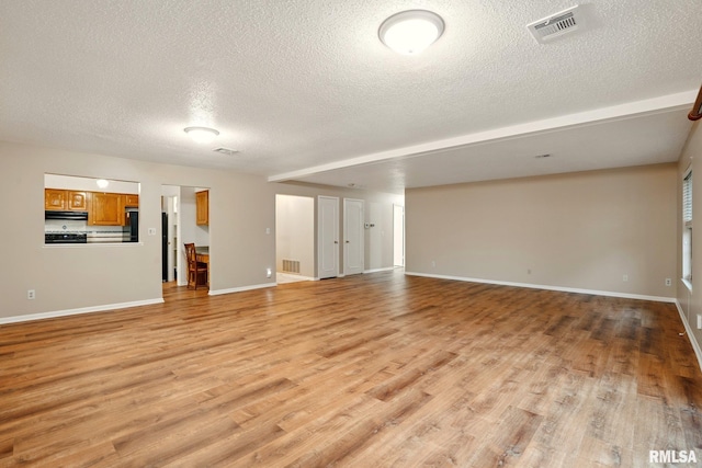 1360 Kimberly Ridge Rd Unit 306, Bettendorf, IA 52722 - unfurnished living room featuring a textured ceiling, light wood-style flooring, and baseboards