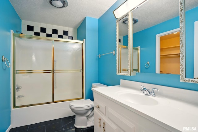 1360 Kimberly Ridge Rd Unit 306, Bettendorf, IA 52722 - bathroom featuring a textured ceiling, vanity, toilet, shower / bath combination with glass door, and tile patterned floors