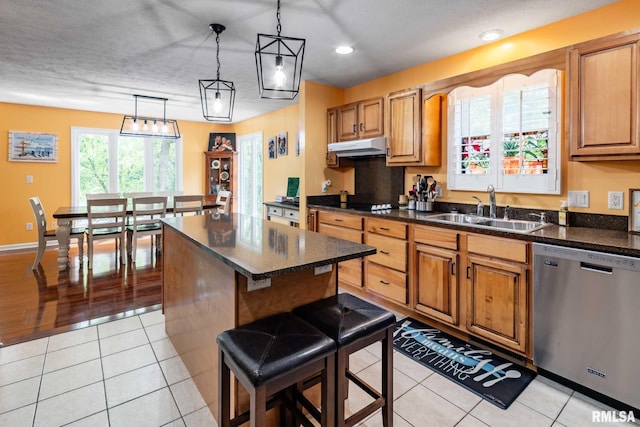 605 Lakeshore Dr S, Goreville, IL 62939 - kitchen with stainless steel dishwasher, a kitchen island, under cabinet range hood, light tile patterned floors, and decorative light fixtures